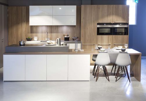 Witte keuken met hout en kookeiland inclusief aanleunende tafel vooraanzicht